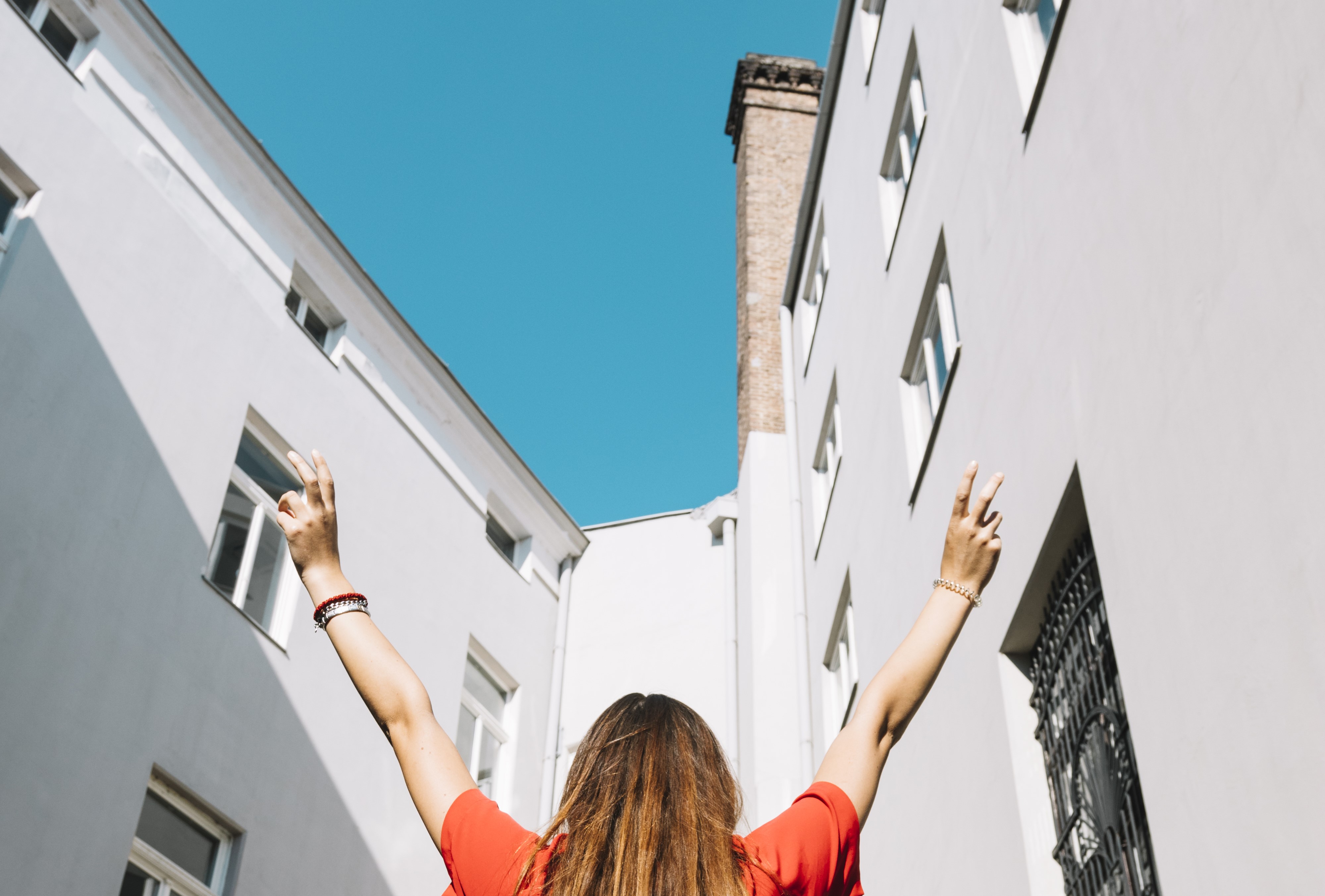 faible angle de vue d une femme levant les bras pres d un immeuble residentiel